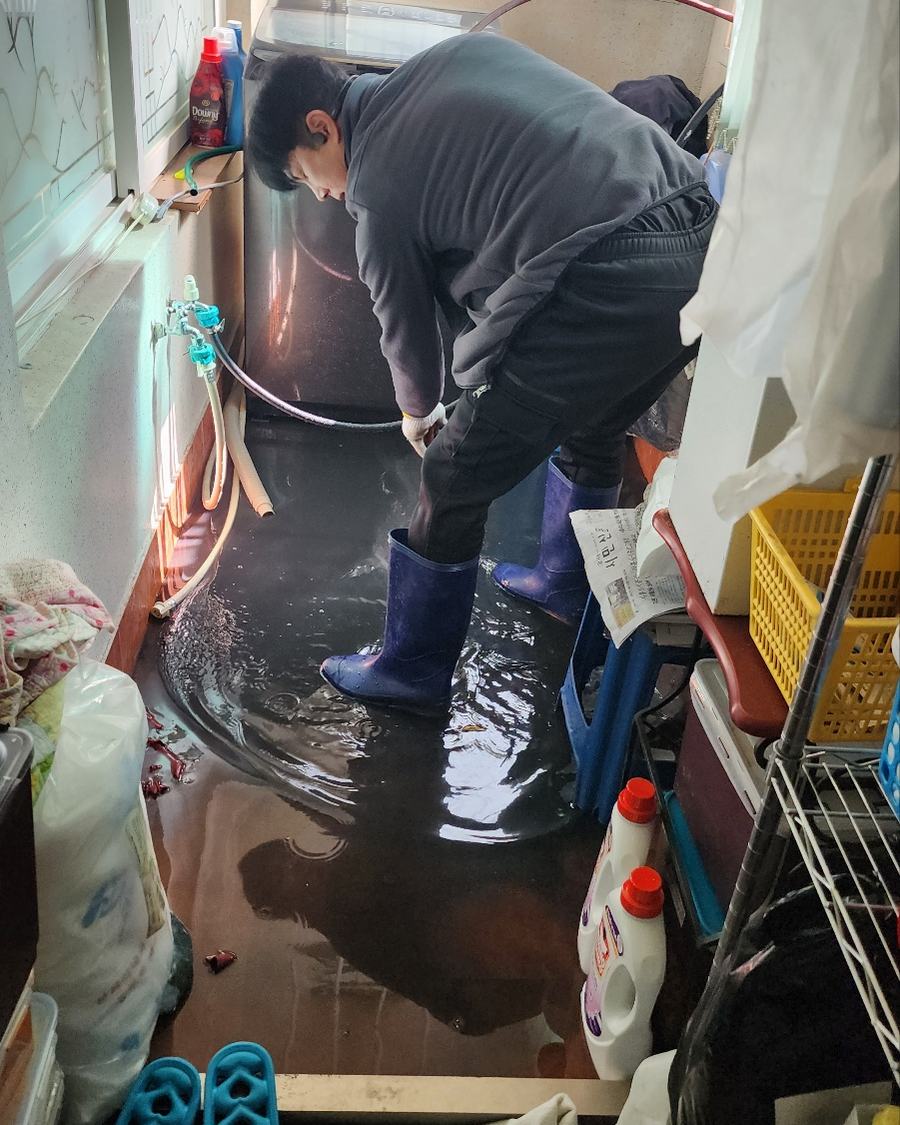 물이 찬 다용도실에서 배수 작업 중인 기사
